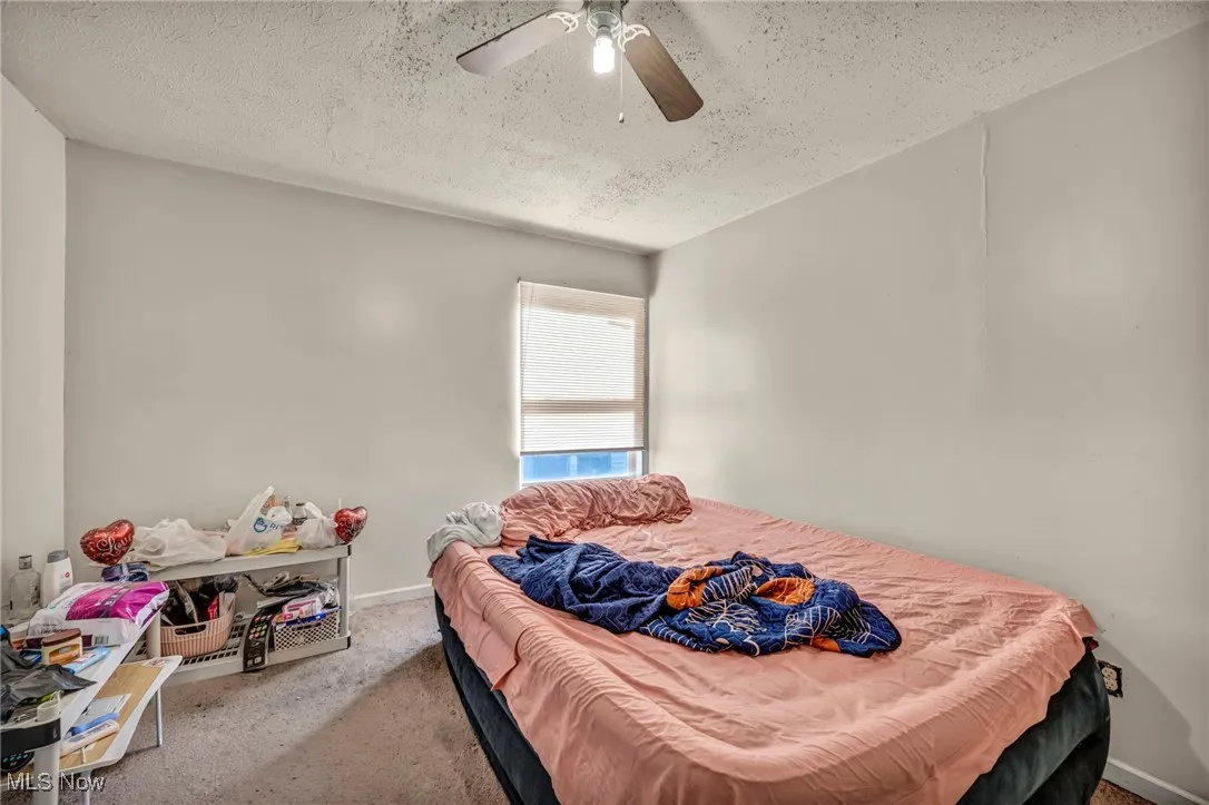 Carpeted bedroom featuring a textured ceiling and ceiling fan