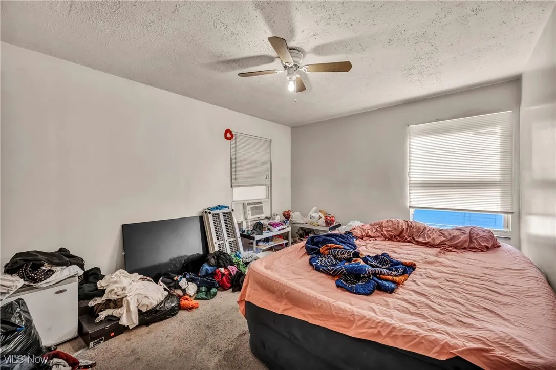 Bedroom with carpet flooring, a textured ceiling, and ceiling fan