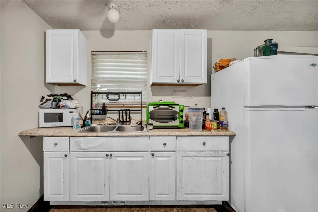 Kitchen with white appliances, white cabinets, and a textured ceiling
