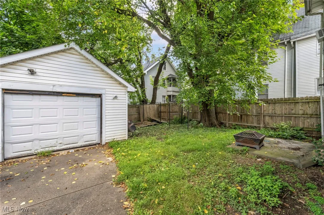 View of yard featuring an outdoor fire pit, driveway, an outbuilding, and a detached garage