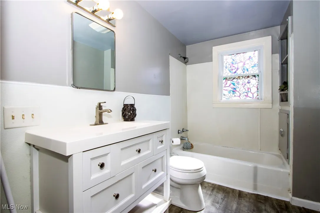 Full bathroom featuring washtub / shower combination, vanity, and dark wood finished floors