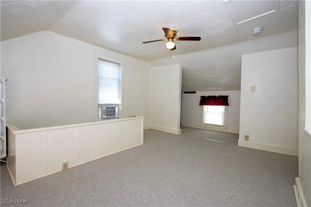 Additional living space featuring carpet floors, ceiling fan, and lofted ceiling