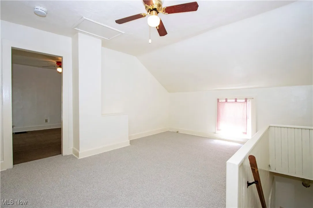 Additional living space with a ceiling fan, vaulted ceiling, carpet, and radiator heating unit