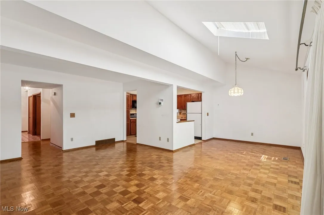 Unfurnished living room with a skylight and high vaulted ceiling