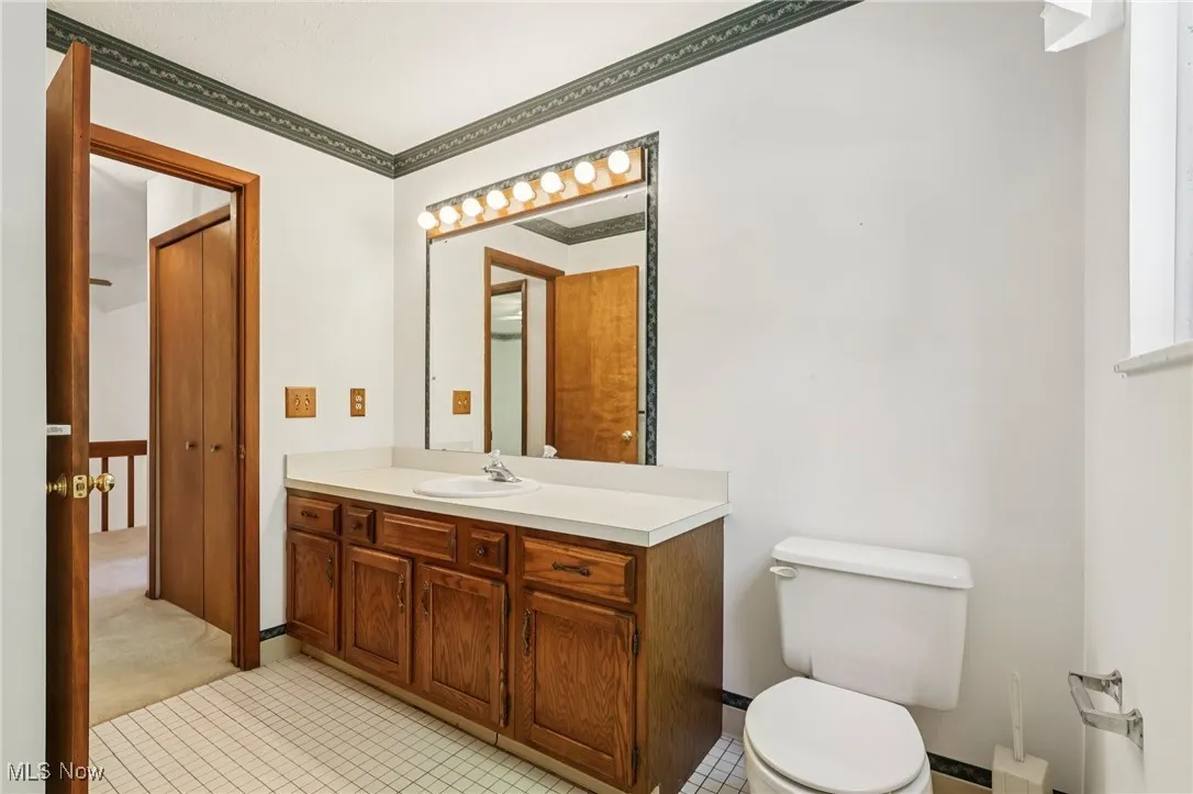 Half bathroom featuring vanity, light tile patterned flooring, and ornamental molding
