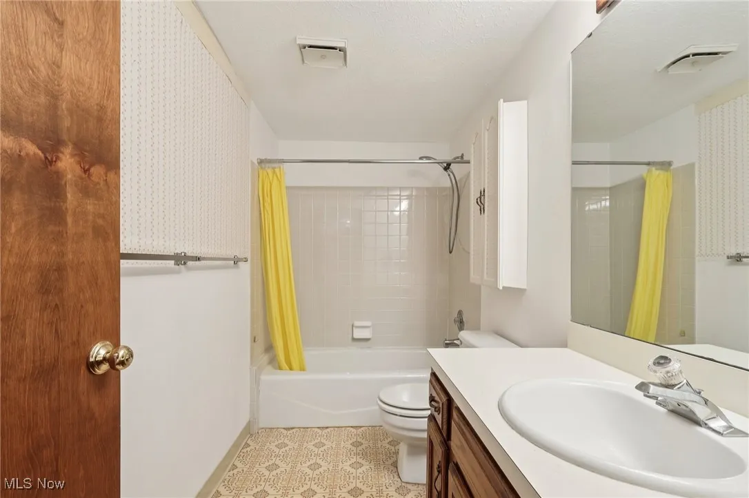 Bathroom featuring shower / bath combination with curtain, vanity, a textured ceiling, and light tile patterned flooring