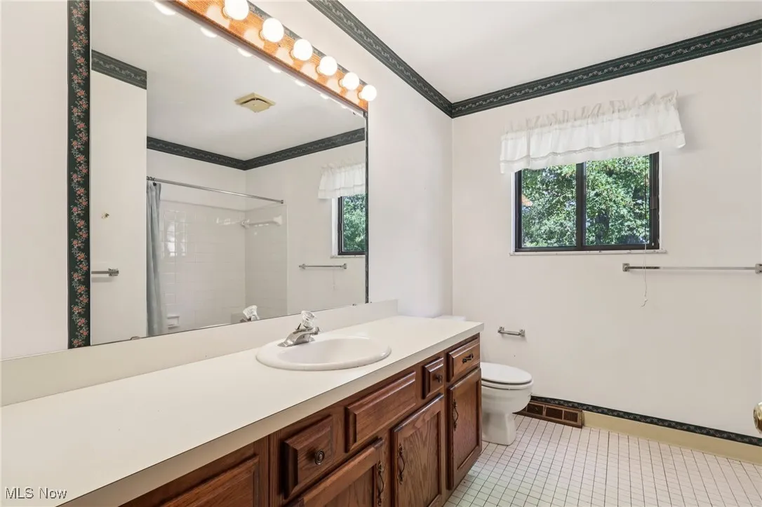 Full bath featuring vanity, ornamental molding, light tile patterned floors, healthy amount of natural light, and a shower with curtain