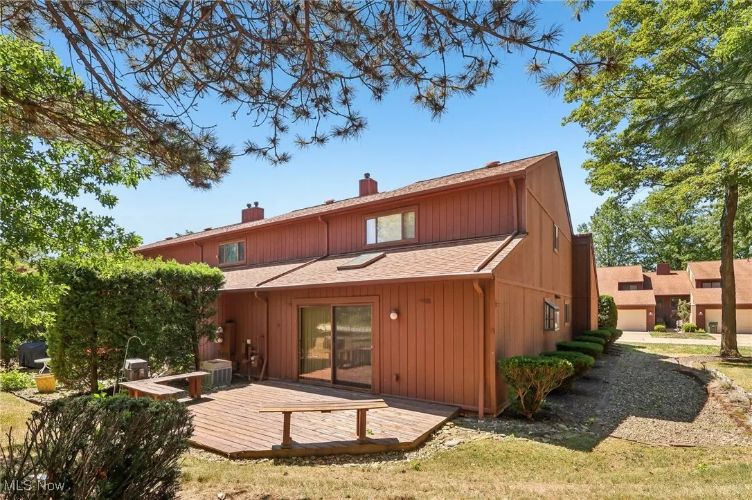 Rear view of house with a chimney, a deck, and roof with shingles