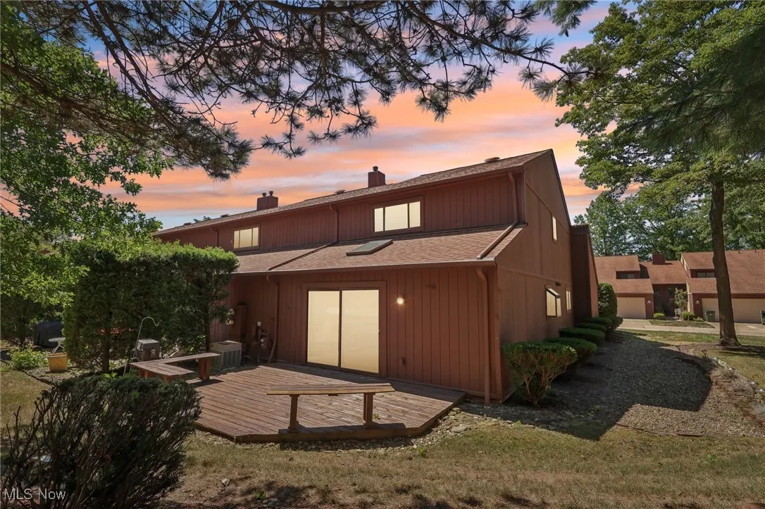 Rear view of house featuring a chimney, a deck, and roof with shingles