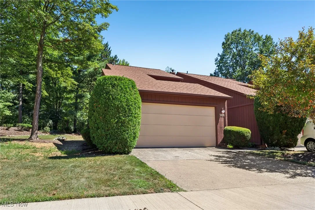 View of front of property with a shingled roof, driveway, an attached garage, and a front yard
