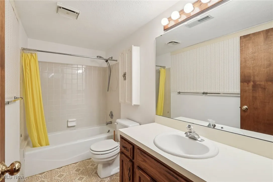 Bathroom featuring shower / tub combo, vanity, and a textured ceiling