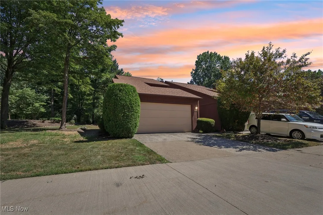 View of front of property with driveway, a garage, a shingled roof, and a lawn