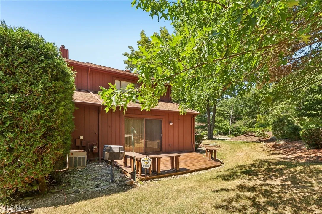 Back of property featuring a chimney, a deck, and a lawn