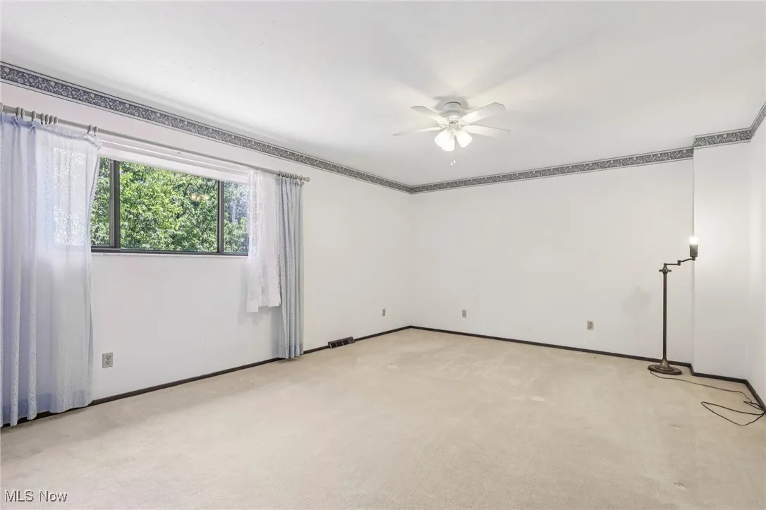 Unfurnished room with light carpet and a ceiling fan