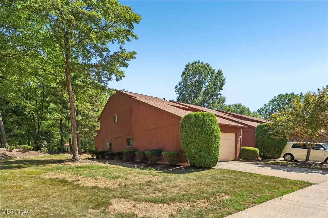 View of side of home featuring an attached garage, concrete driveway, and a yard