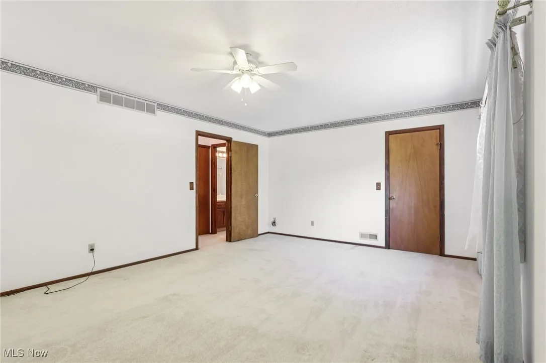 Carpeted spare room featuring baseboards and a ceiling fan