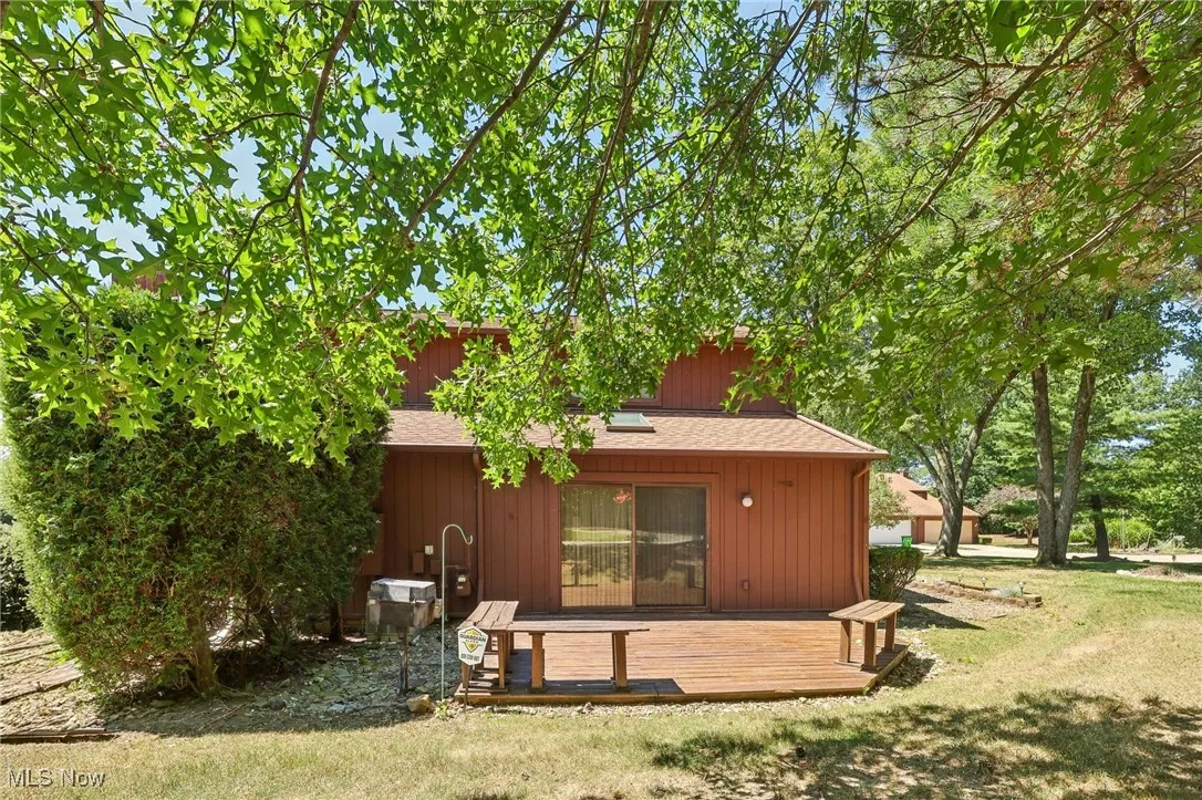 Back of house with a wooden deck, a yard, and roof with shingles