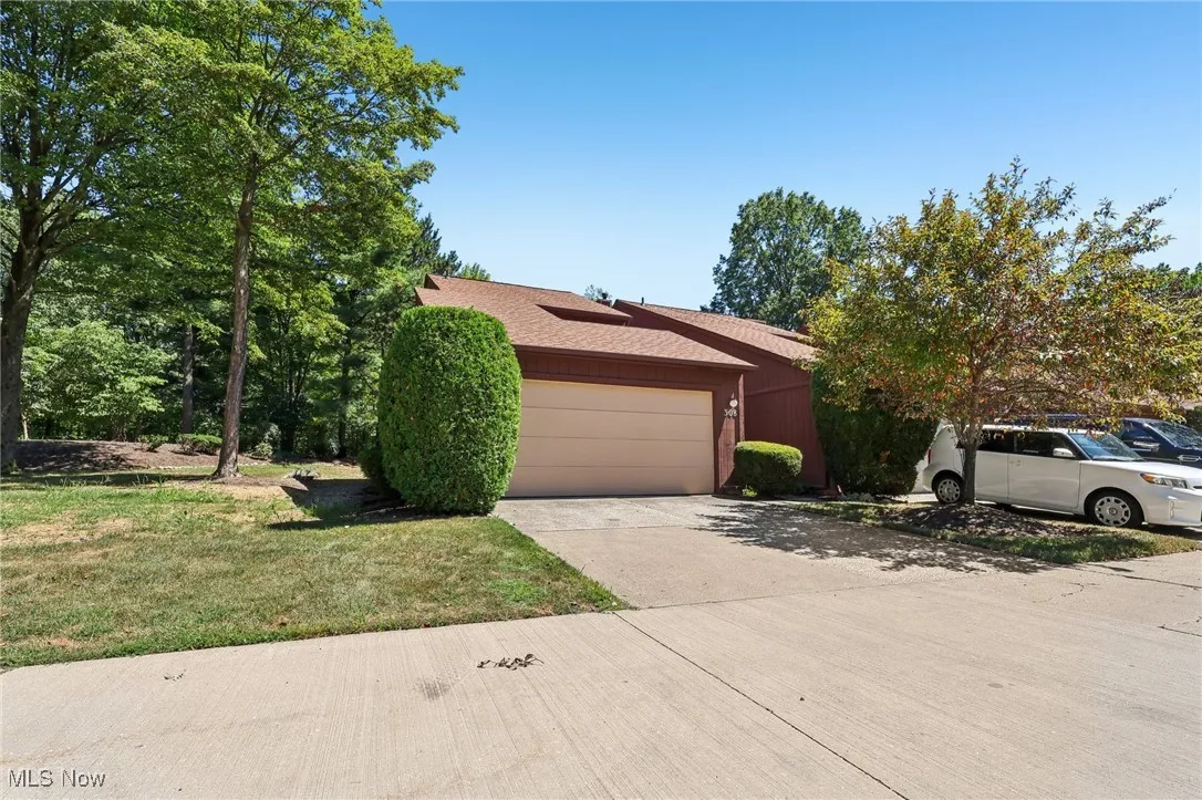 View of front of house with driveway, a shingled roof, an attached garage, and a front lawn