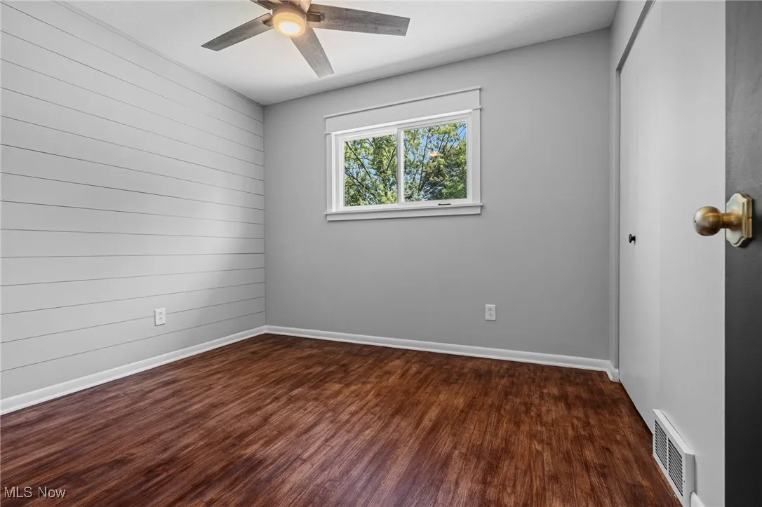 Bedroom #2 with dark wood-style floors, ceiling fan/light, and freshly painted