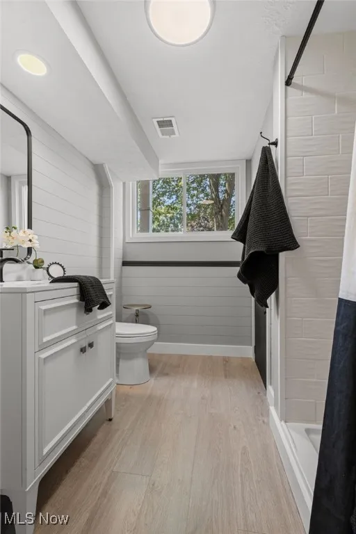 Full bathroom on lower level featuring vanity, tiled shower, laminate flooring and new light fixtures