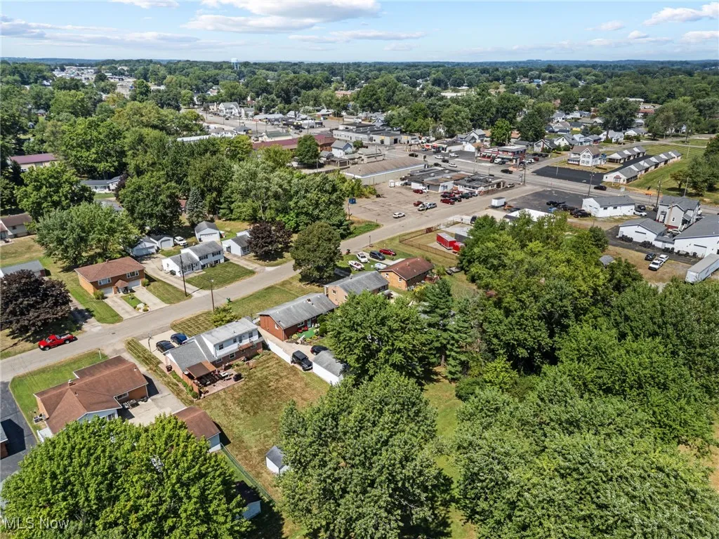 Aerial view of property's location with nearby suburban area and a tree filled landscape