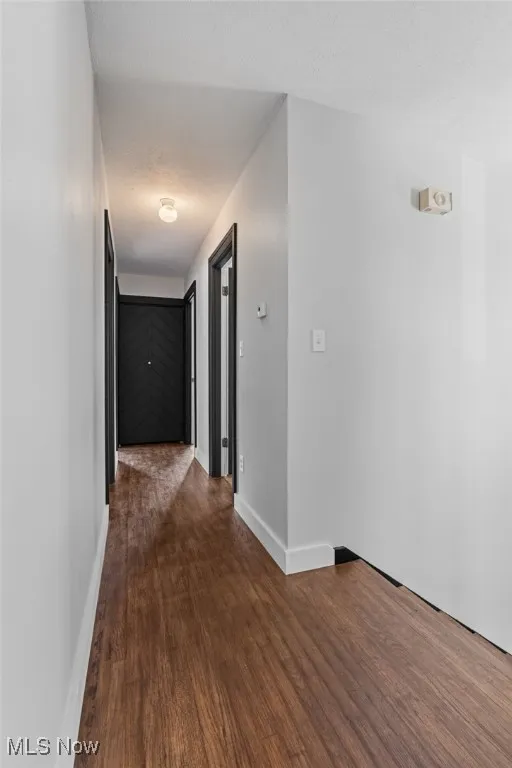 Corridor featuring dark wood-style flooring and a textured ceiling