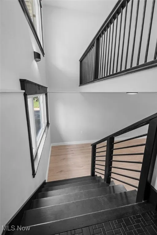 Stairs featuring wood finished floors and a towering ceiling