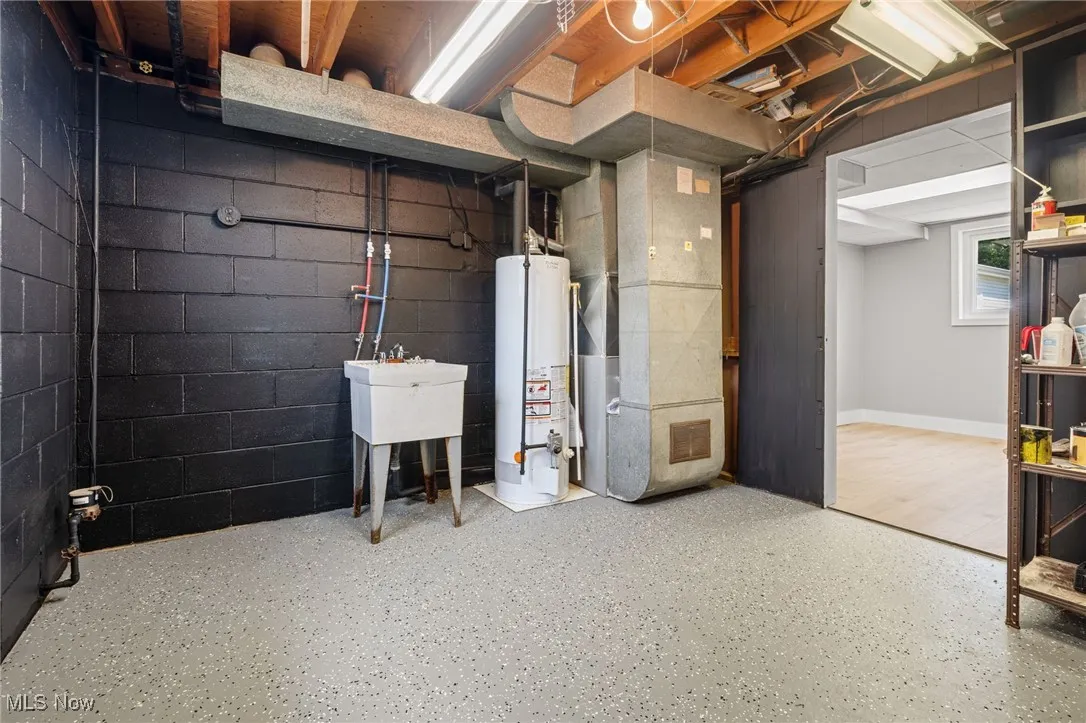 Below grade area featuring heating unit and gas water heater, laundry & utility sink