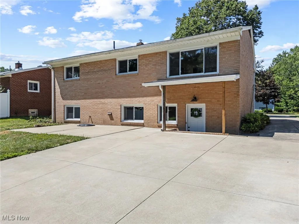 Back of property with brick exterior and concrete driveway