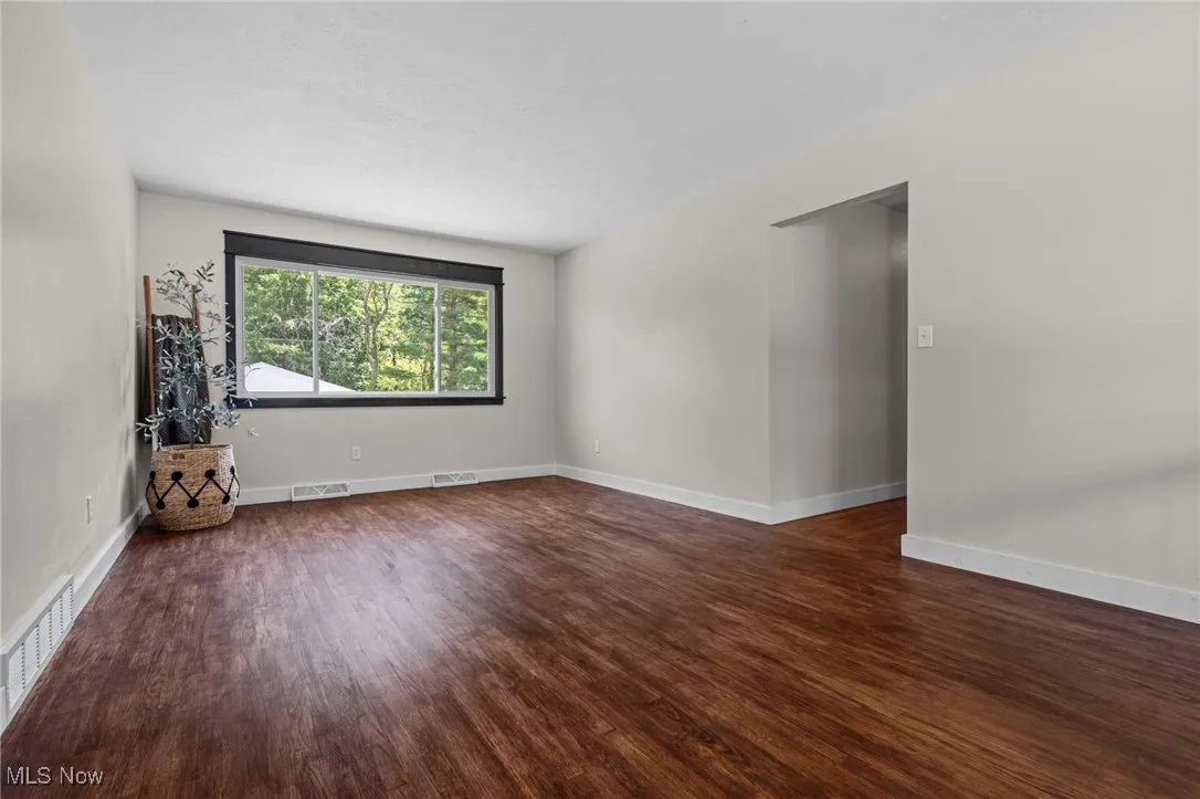 Living room with dark wood-style flooring and picture windows