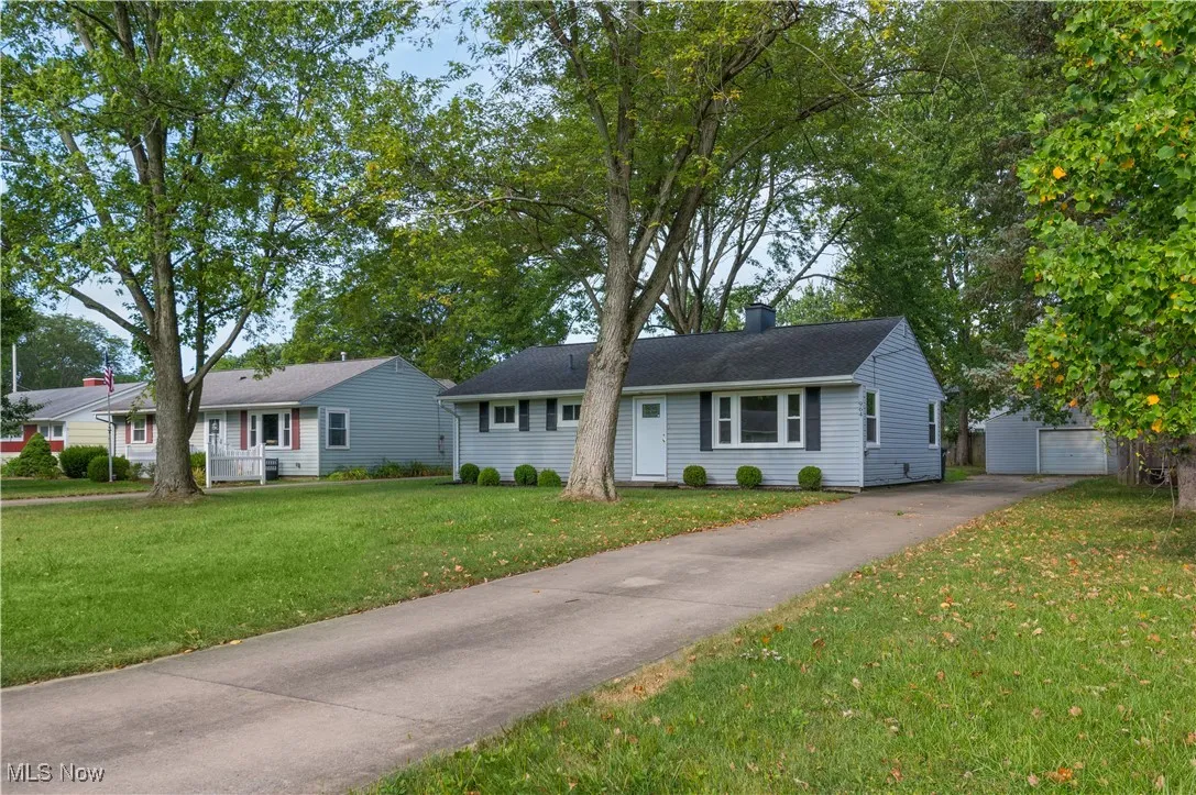 Ranch-style home with an outbuilding, a front yard, a chimney, a detached garage, and driveway
