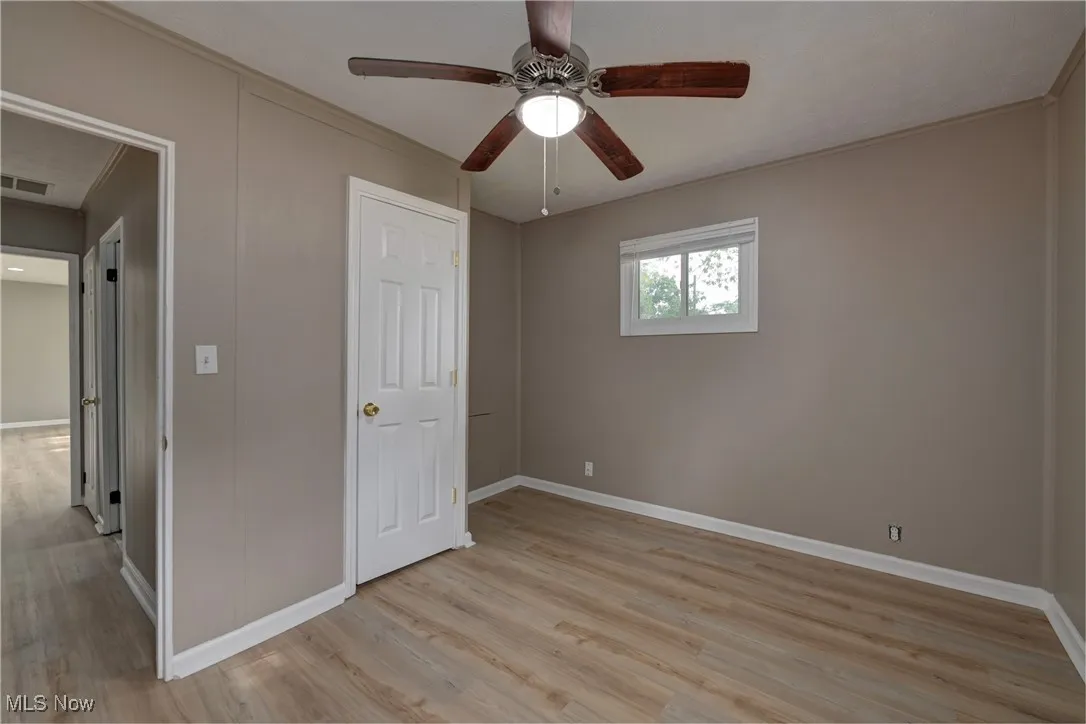 Unfurnished bedroom with crown molding, light wood-style flooring, and a ceiling fan
