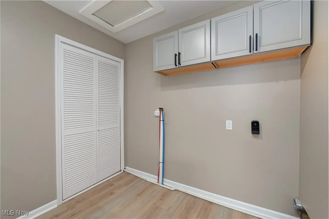 Washroom with light wood-style floors and attic access