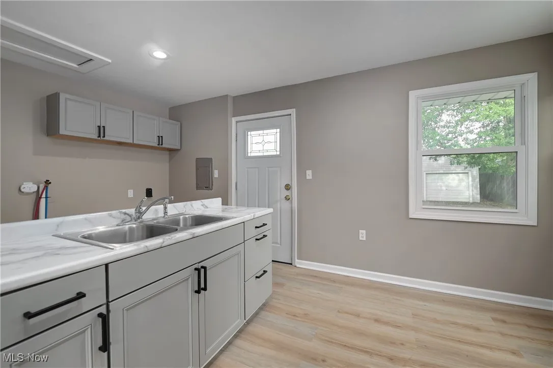 Kitchen with gray cabinetry, light countertops, light wood-style floors, recessed lighting, and electric panel