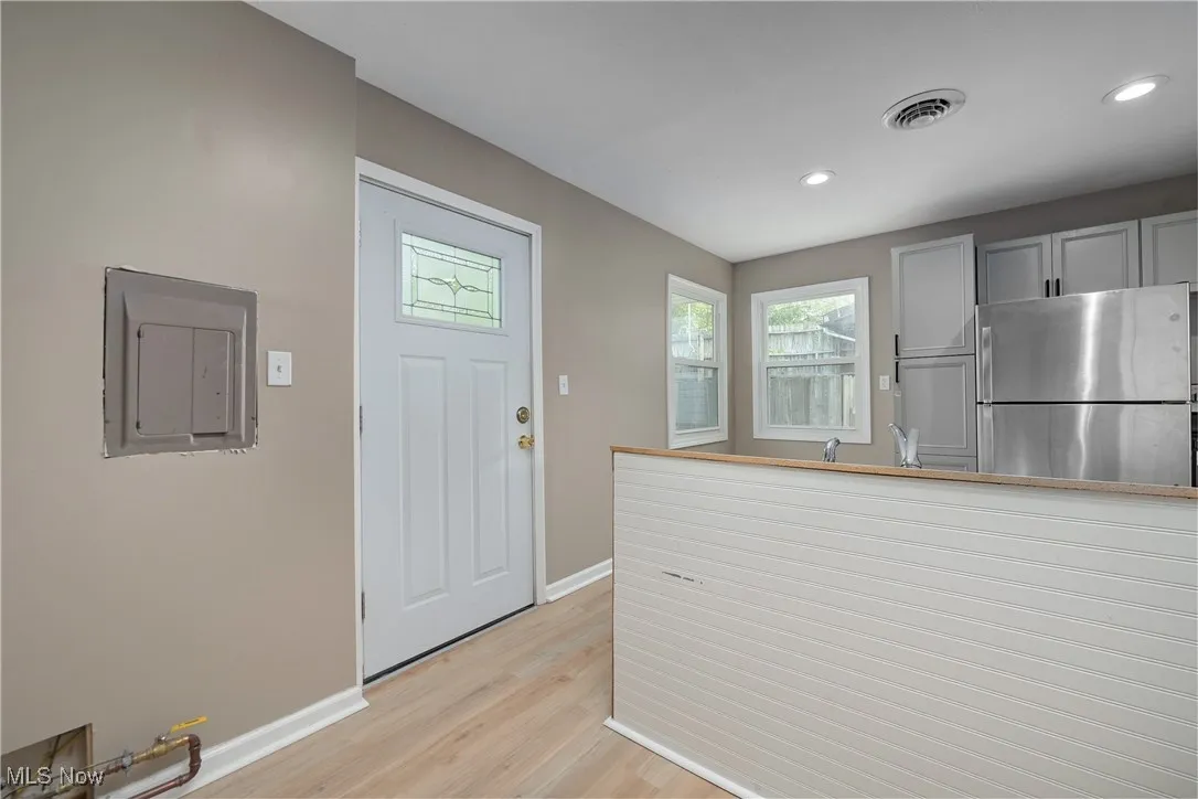 Kitchen with freestanding refrigerator, electric panel, light wood-style floors, recessed lighting, and white cabinets