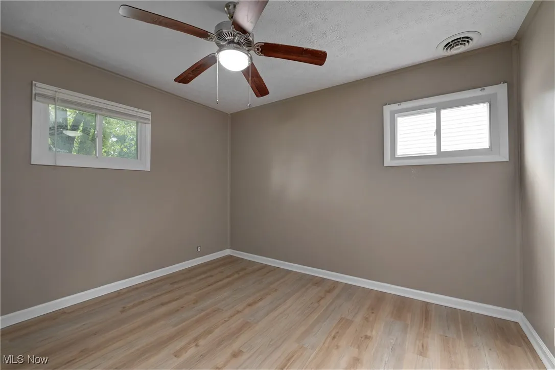 Spare room with light wood finished floors, a textured ceiling, and a ceiling fan