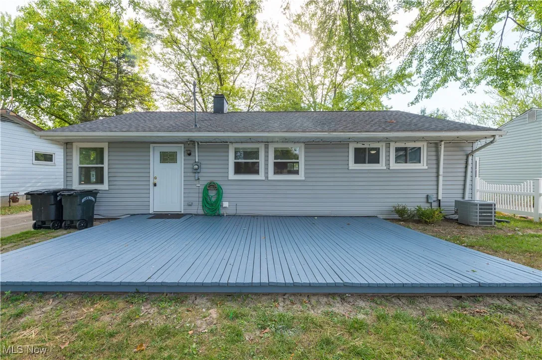 Back of property featuring a wooden deck, a chimney, and a shingled roof