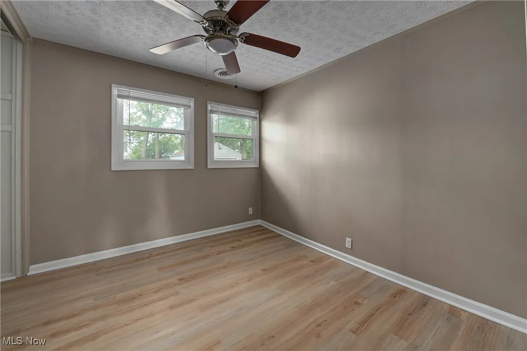 Unfurnished room featuring a textured ceiling, light wood-style floors, and ceiling fan