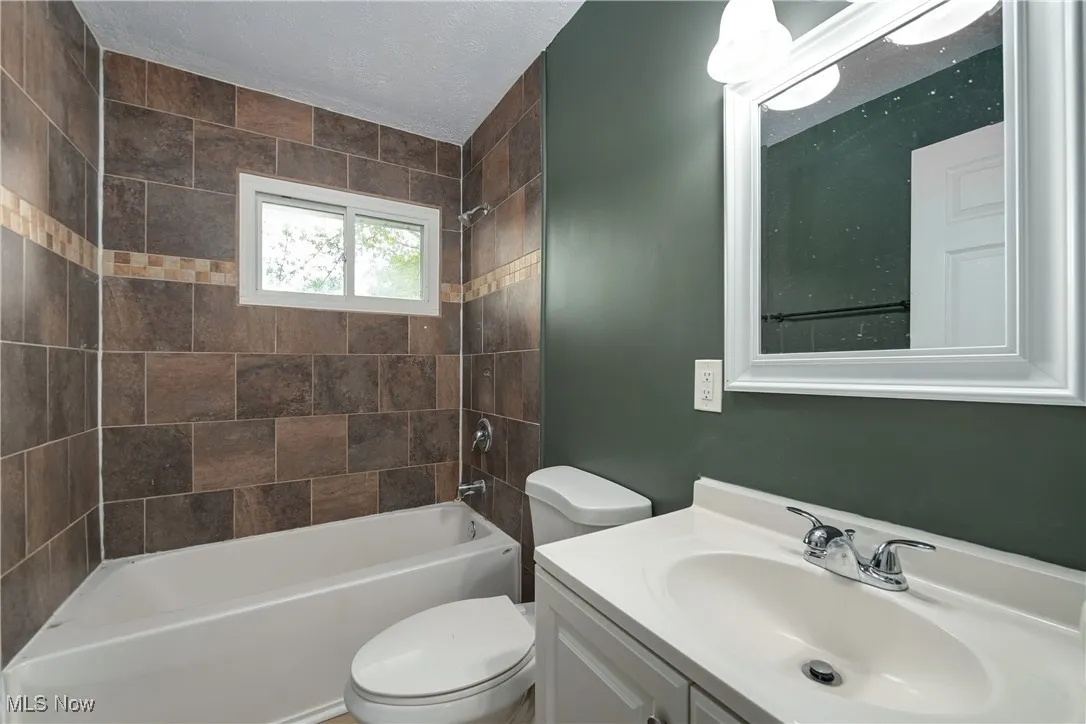 Full bathroom featuring washtub / shower combination, vanity, and a textured ceiling