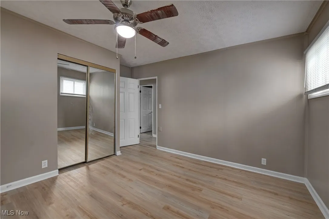 Unfurnished bedroom featuring light wood-type flooring, ceiling fan, a closet, and a textured ceiling