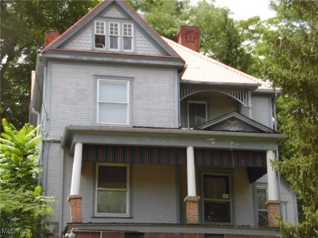 Victorian-style house with a chimney and covered porch