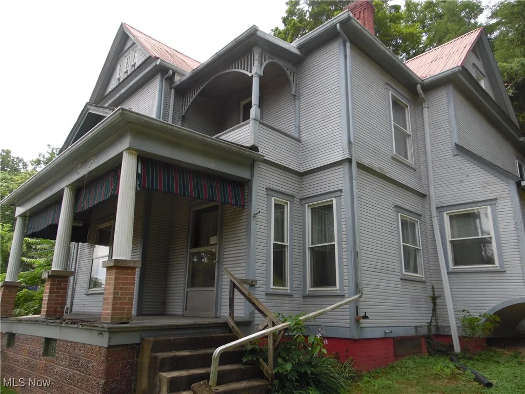 Victorian-style house with a chimney, covered porch, and a metal roof