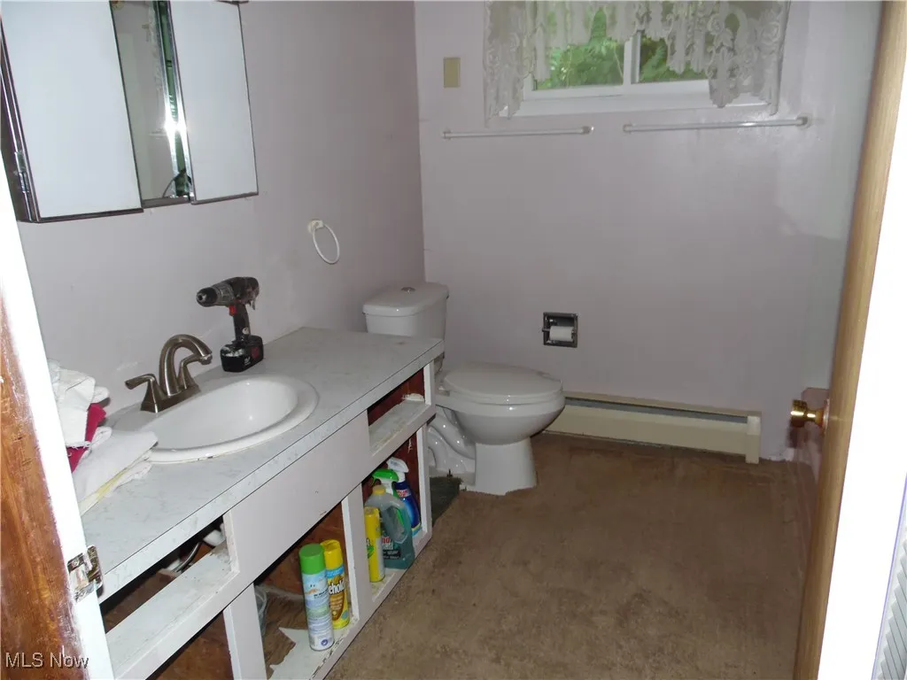 Half bath with baseboard heating and vanity