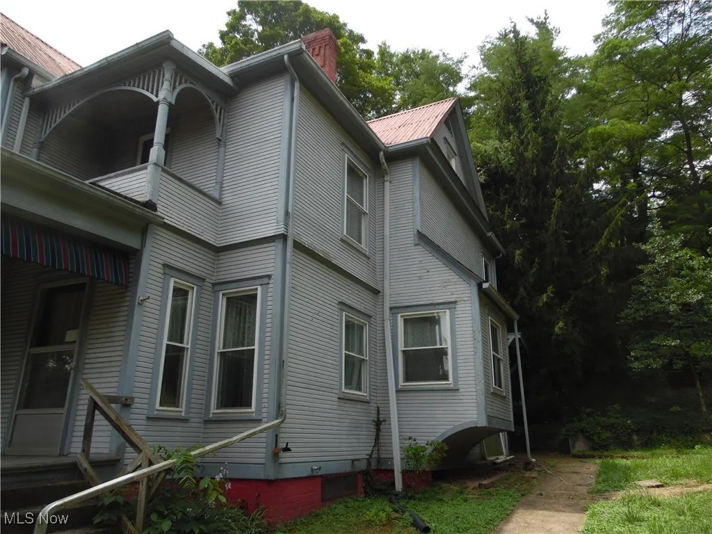 View of side of home with a chimney and a metal roof