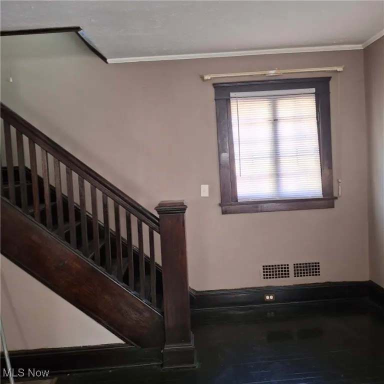 Staircase with crown molding and hardwood / wood-style flooring