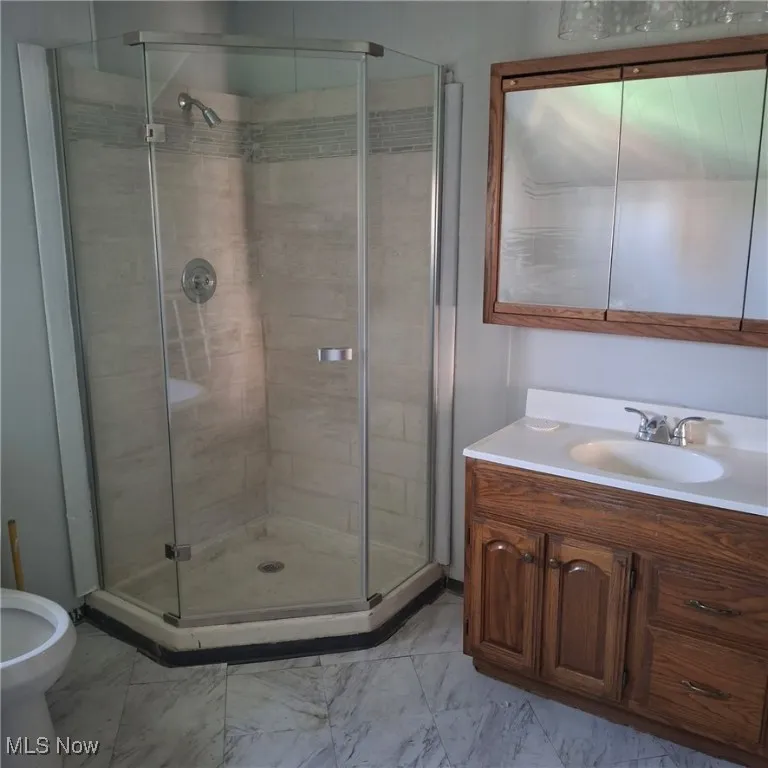 Bathroom with a shower stall, vanity, light marble finish floors, and a bidet