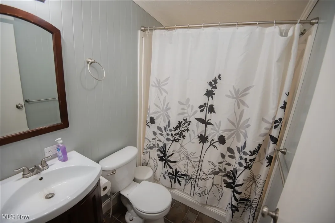 Full bath with vanity, a shower with curtain, and wood walls