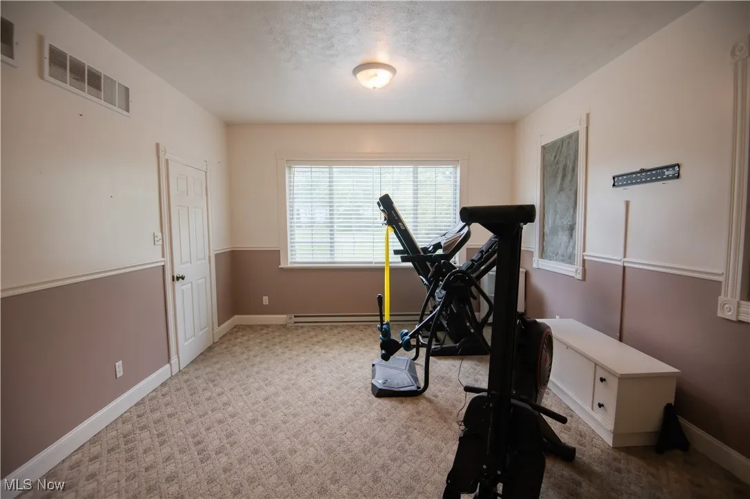 Exercise room featuring carpet and a textured ceiling. 4th bedroom