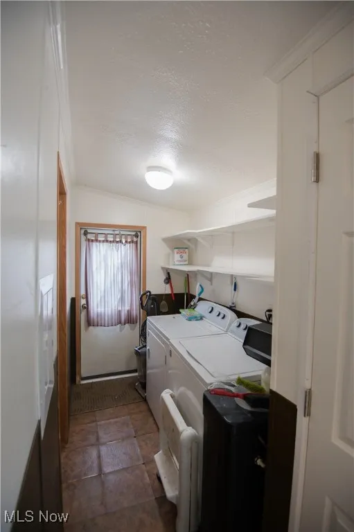 Laundry room featuring a textured ceiling, washer and clothes dryer, and dark stone finish flooring