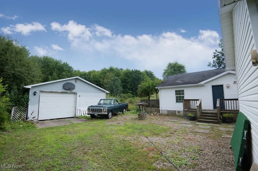 View of green lawn featuring a detached garage, an outdoor structure, and driveway